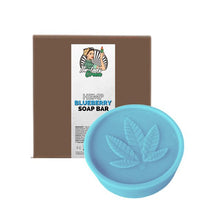 Load image into Gallery viewer, A round, light blue soap bar embossed with a hemp leaf sits in front of a brown packaging box. The label on the box reads "Lady Green Hemp Soap Bar" by Green Apron and features an illustration of a person holding a plant intertwined with sugarcane.
