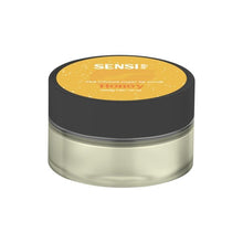 Load image into Gallery viewer, A small, round container with a black lid labeled "Sensi Skin" on top with "100mg CBD Sugar Lip Scrub," and "Honey" beneath it on a yellow background. The transparent container reveals the vegan-friendly lip scrub inside.